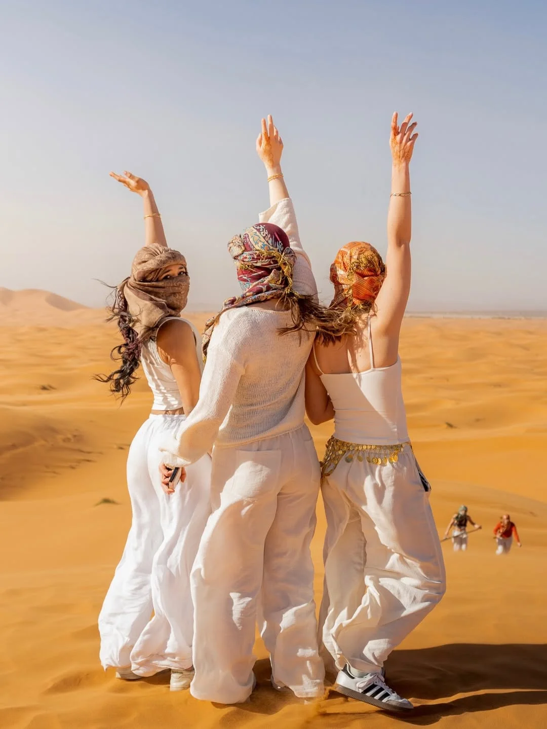 Travellers celebrating on the golden dunes of Merzouga